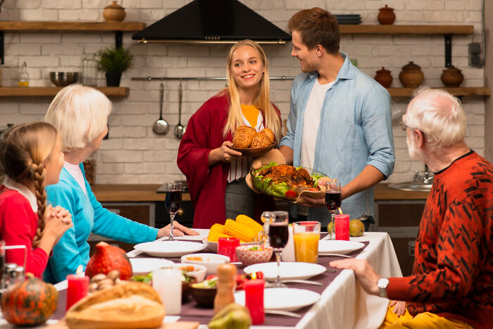 A young couple serving food at a family dinner highlighting unfair relationships due to traditional gender roles.
