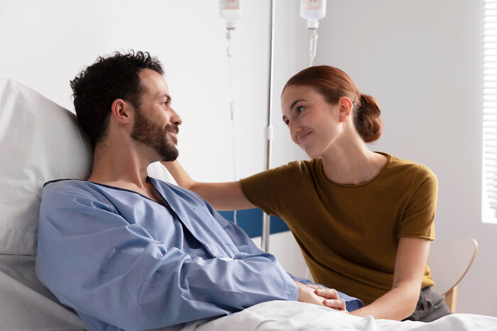 Man in hospital bed and woman showing care and concern, highlighting unfair relationships due to traditional gender roles.