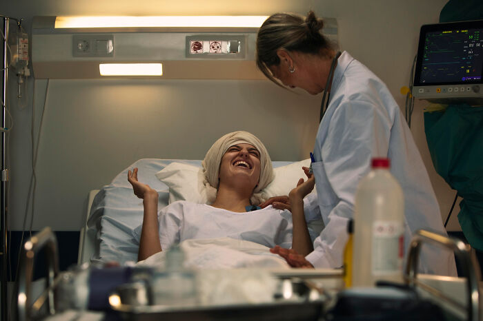 Patient in hospital bed laughing with doctor beside her, set in a hospital room related to scary ghost stories hospital work.