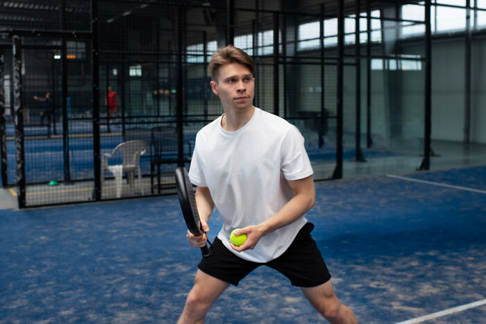 Young man playing paddle tennis indoors, illustrating the impact of gender roles in unfair relationships.