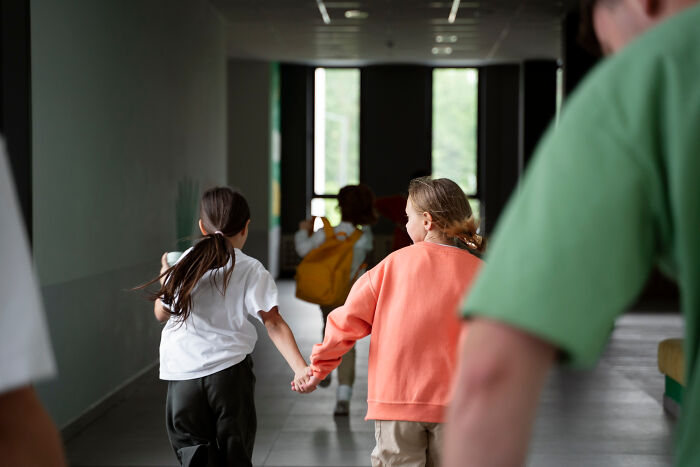 Children holding hands and running down a dim hospital hallway, evoking scary ghost stories at hospital work settings.