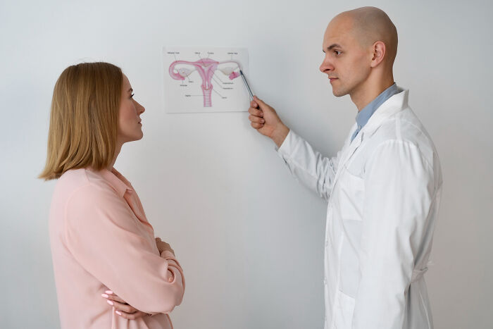 Doctor explaining reproductive system diagram to woman, highlighting highly disturbing things folks were told about health.
