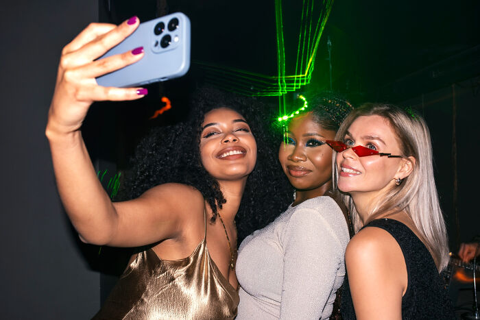 Three young women taking a selfie at a party with a smartphone.