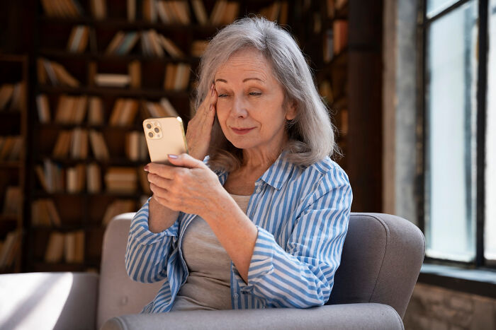 Older woman with confused expression struggling with technology while using a smartphone, depicting parents with bad technology skills.