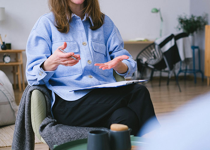Woman in a blue shirt explaining mental health myths during a counseling session in a cozy, well-lit room.