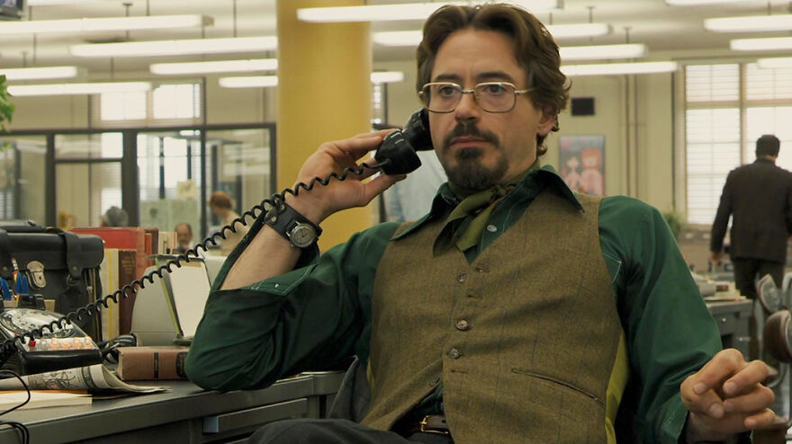 Man in vintage clothing on phone in an office setting, representing movies based on true stories that feel impossible to believe.