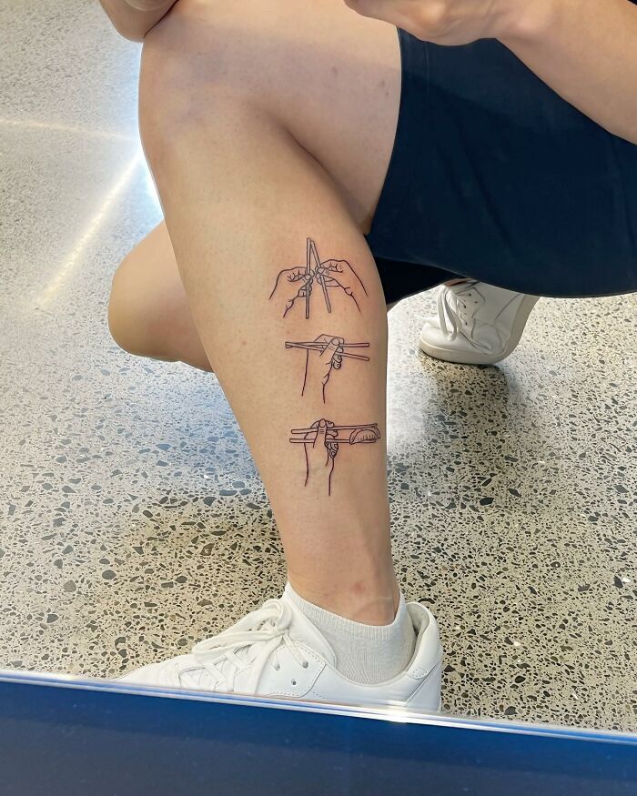 Minimalist tattoo of hands using chopsticks on a person’s lower leg, showcasing unique tattoo artist creativity and style.