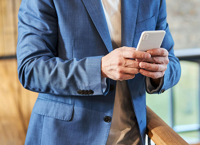 Man in blue blazer holding smartphone, illustrating waiter assumed 40 change was tip in a casual setting. Man in blue blazer holding smartphone, illustrating waiter assumed 40 change was tip in a casual setting.