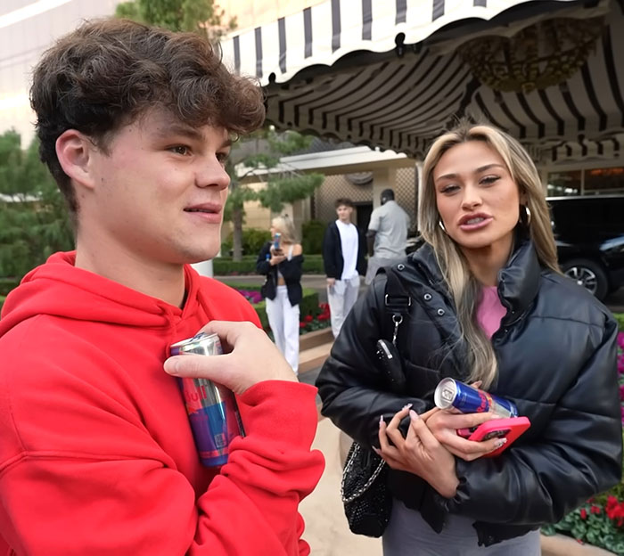 Young adult star and YouTube prankster holding drinks outside a building with others in the background. Young adult star and YouTube prankster holding drinks outside a building with others in the background.