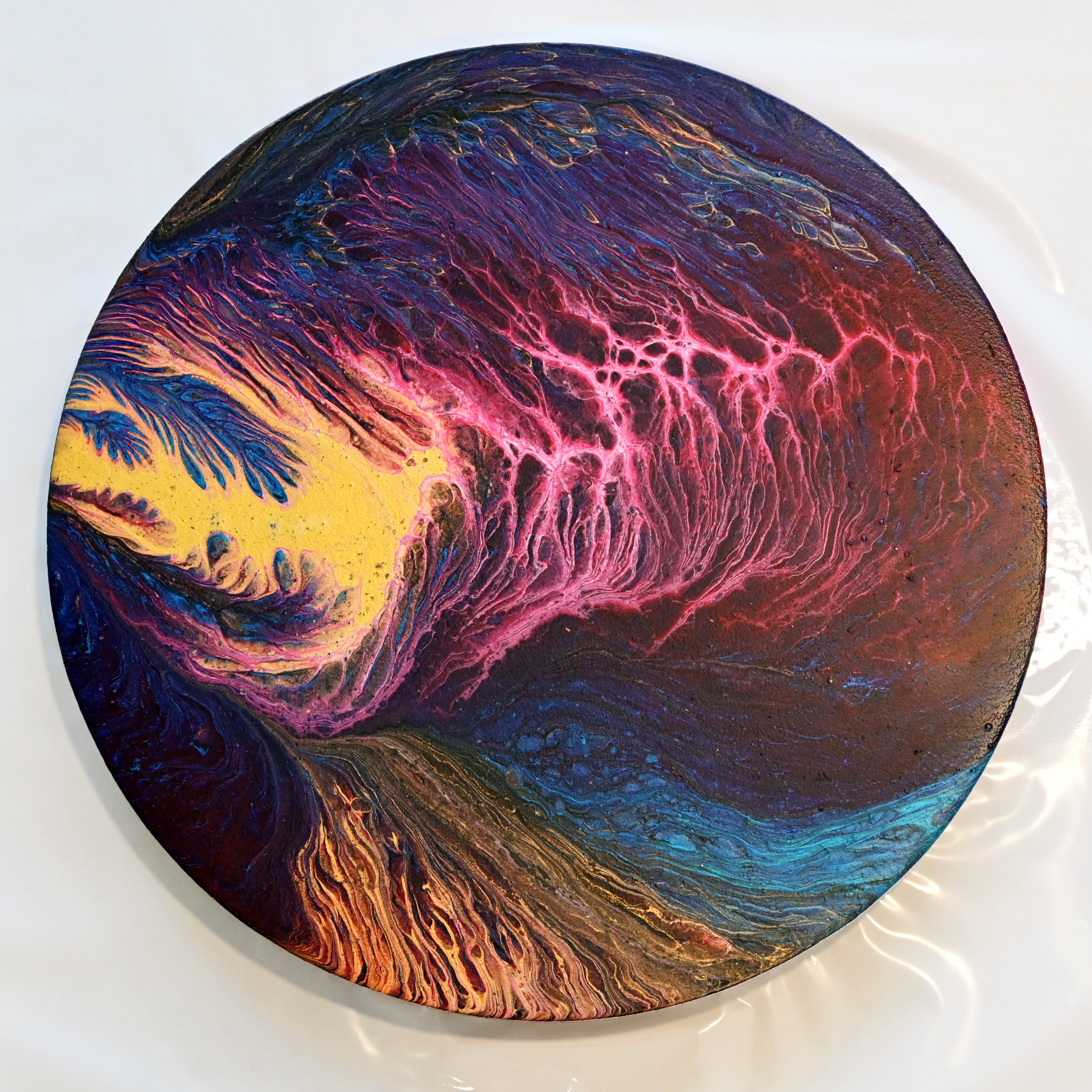 Circular acrylic pour art with vibrant colors and cells created using a budget-friendly acrylic pour technique.