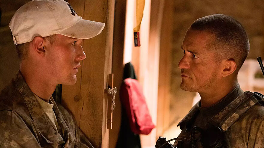 Two soldiers in uniform face each other in a tense conversation in a scene from movies based on true stories.