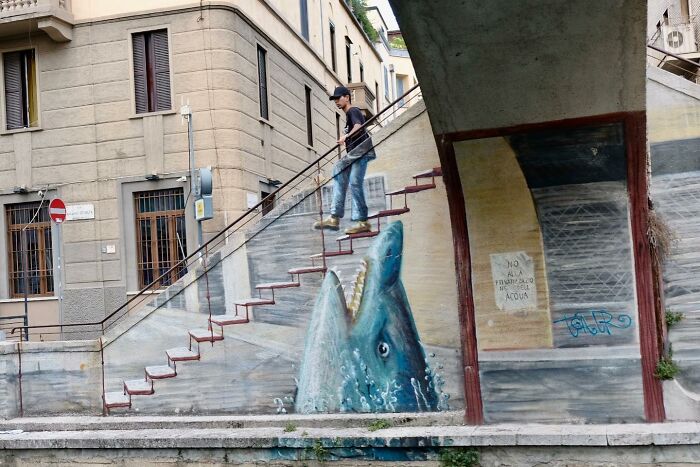 A man walking down stairs with street art of a shark on Istanbul’s streets, capturing vibrant urban life.