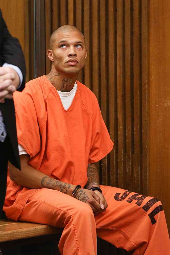Man known as world's hottest felon wearing orange jail uniform with tattoos, sitting in courtroom looking upward Man known as world's hottest felon wearing orange jail uniform with tattoos, sitting in courtroom looking upward