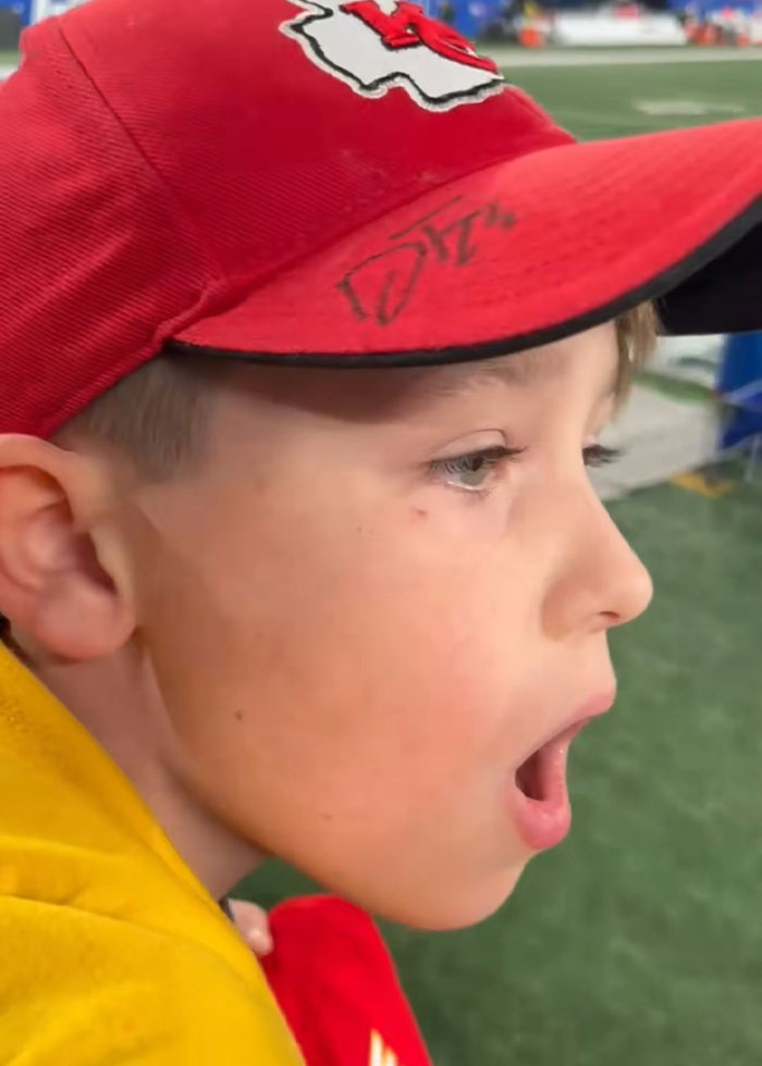 Young boy wearing a red Kansas City Chiefs cap, reacting in a stadium, related to viral Kansas City Karen incident.