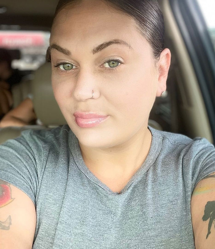 Woman with tattooed arms and nose ring sitting in a car, sharing her story about daughter getting bullied for clothes. Woman with tattooed arms and nose ring sitting in a car, sharing her story about daughter getting bullied for clothes.