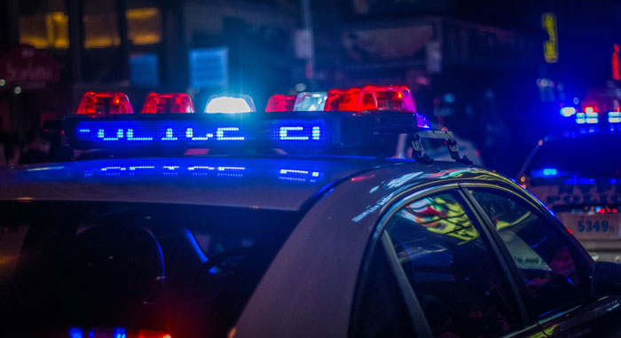 Police car with flashing lights at night responding to a woman's unhinged act after breaking into boyfriend’s home incident. Police car with flashing lights at night responding to a woman's unhinged act after breaking into boyfriend’s home incident.