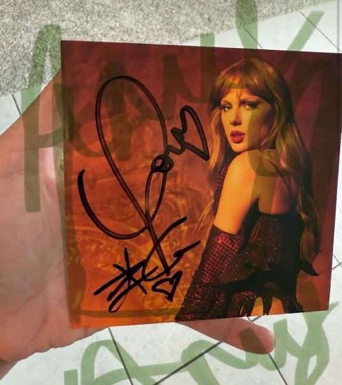 Hand holding a Taylor Swift album signed by Travis Kelce, sparking tradwife Taylor Swift fans' fury over autograph. Hand holding a Taylor Swift album signed by Travis Kelce, sparking tradwife Taylor Swift fans' fury over autograph.