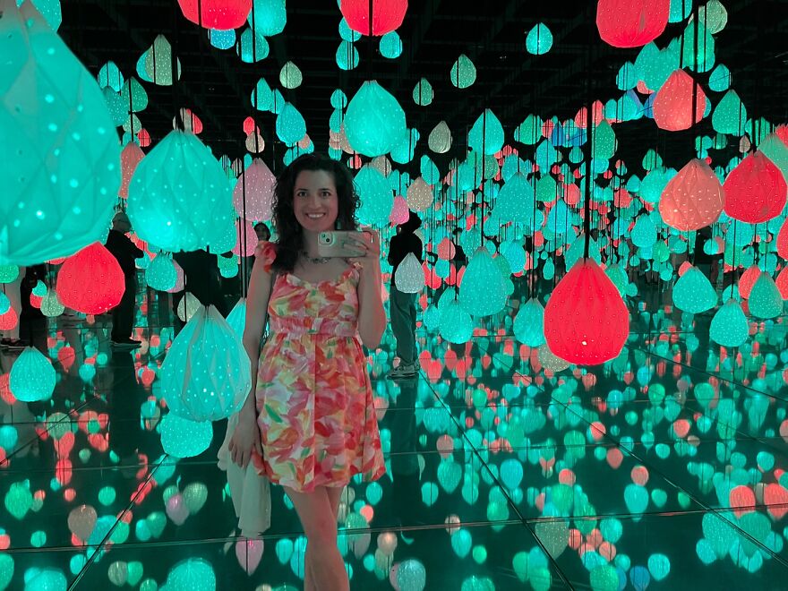 Woman taking selfie in colorful illuminated room filled with hanging lights, representing woman getting responses after billboard campaign. Woman taking selfie in colorful illuminated room filled with hanging lights, representing woman getting responses after billboard campaign.