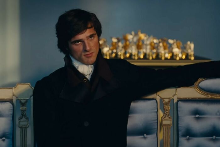 Young man in dark period costume sitting on ornate blue and gold settee in a scene from Wuthering Heights trailer. Young man in dark period costume sitting on ornate blue and gold settee in a scene from Wuthering Heights trailer.