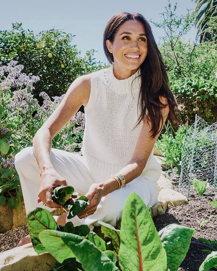 Meghan Markle enjoying gardening outdoors, smiling and picking fresh greens in a sunny natural setting. Meghan Markle enjoying gardening outdoors, smiling and picking fresh greens in a sunny natural setting.