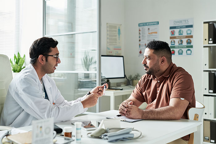 Man consulting a doctor in a medical office, reflecting a woman expecting help from ex-husband after leaving him for another man. Man consulting a doctor in a medical office, reflecting a woman expecting help from ex-husband after leaving him for another man.