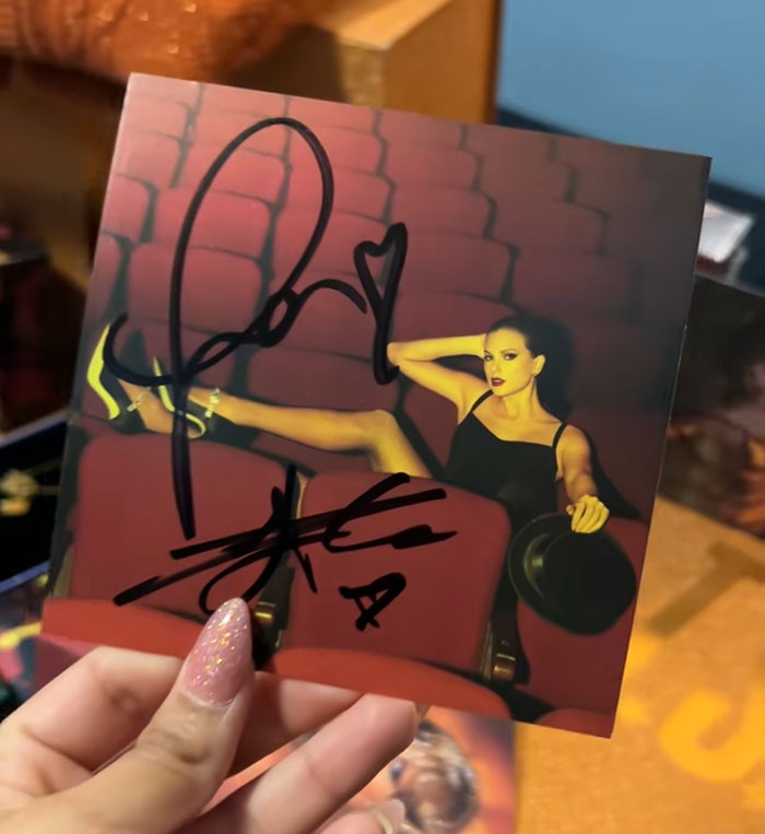 Hand holding a Taylor Swift album autographed by Travis Kelce, causing reactions among Tradwife Taylor Swift fans. Hand holding a Taylor Swift album autographed by Travis Kelce, causing reactions among Tradwife Taylor Swift fans.