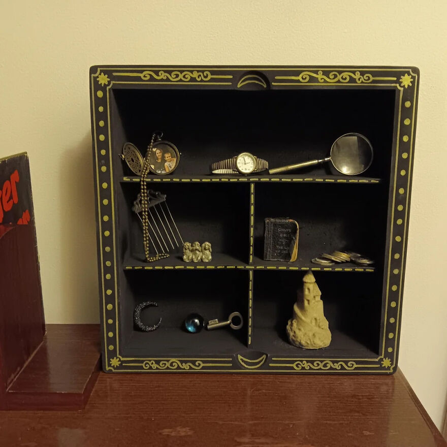 Decorative black shelf with small compartments displaying trinkets and collectibles in a home organization setup.