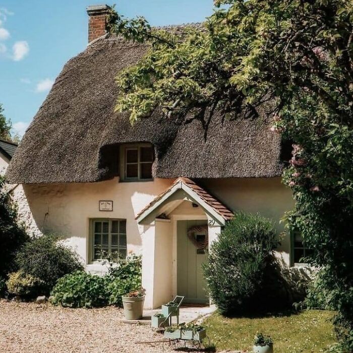 Thatched cottage surrounded by lush gardens and greenery, embodying the charm of dream cottages and gardens.