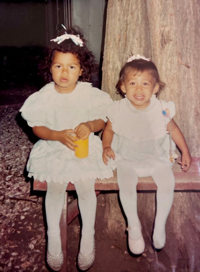 Two young sisters in white dresses sitting on a bench, representing the miracle of sisters discovered alive after 36 years. Two young sisters in white dresses sitting on a bench, representing the miracle of sisters discovered alive after 36 years.