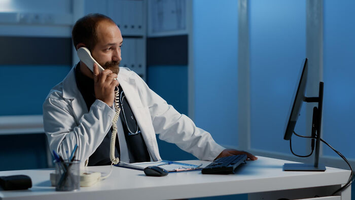 Doctor working late in hospital, talking on the phone and using computer, setting for scary ghost stories hospital work.