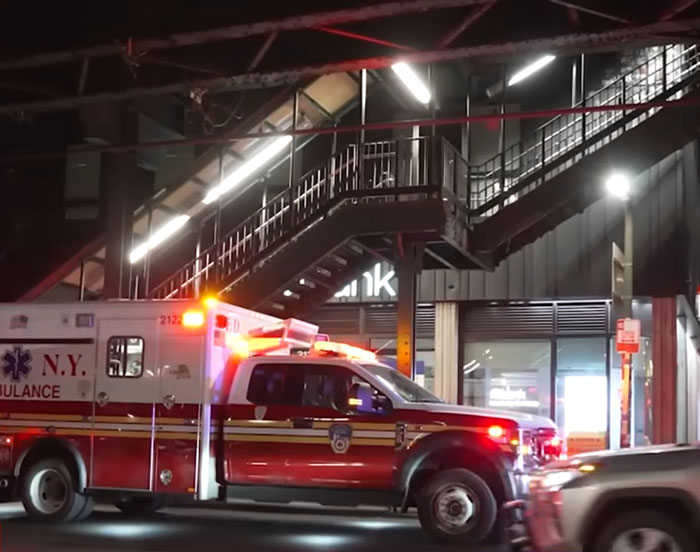 New Yorker Krankenwagen mit Blinklicht unter erhöhten U-Bahn-Gleisen bei Nacht in städtischer Umgebung im Zusammenhang mit einem Vorfall beim Subway-Surfen. New Yorker Krankenwagen mit Blinklicht unter erhöhten U-Bahn-Gleisen bei Nacht in städtischer Umgebung im Zusammenhang mit einem Vorfall beim Subway-Surfen.
