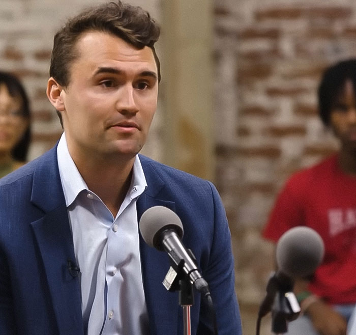 Man in blue blazer speaking into microphone during discussion about Charlie Kirk homework assignment controversy. Man in blue blazer speaking into microphone during discussion about Charlie Kirk homework assignment controversy.
