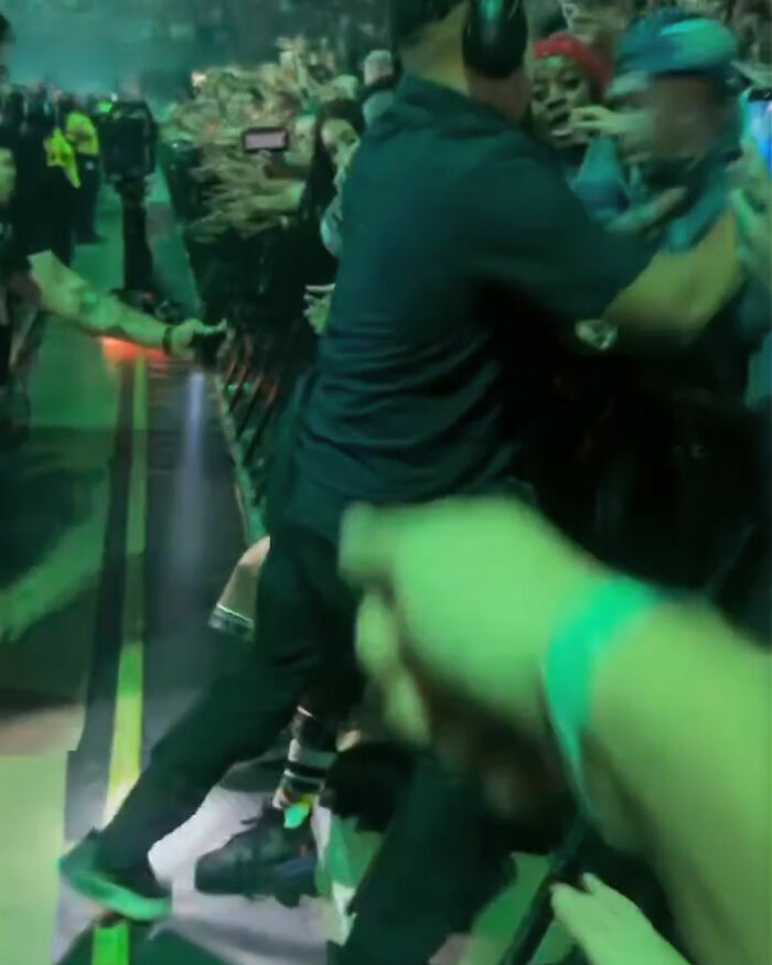 Security personnel restraining a man trying to snatch Billie Eilish during Miami concert, fans visibly outraged in the crowd. Security personnel restraining a man trying to snatch Billie Eilish during Miami concert, fans visibly outraged in the crowd.