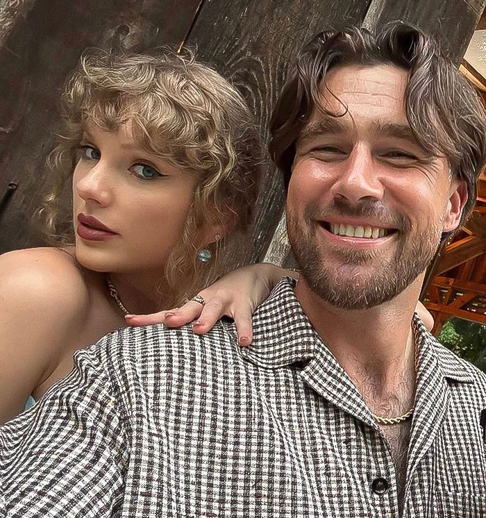 Taylor Swift with Travis Kelce smiling together, fans reacting to autographed albums and tradwife controversy. Taylor Swift with Travis Kelce smiling together, fans reacting to autographed albums and tradwife controversy.