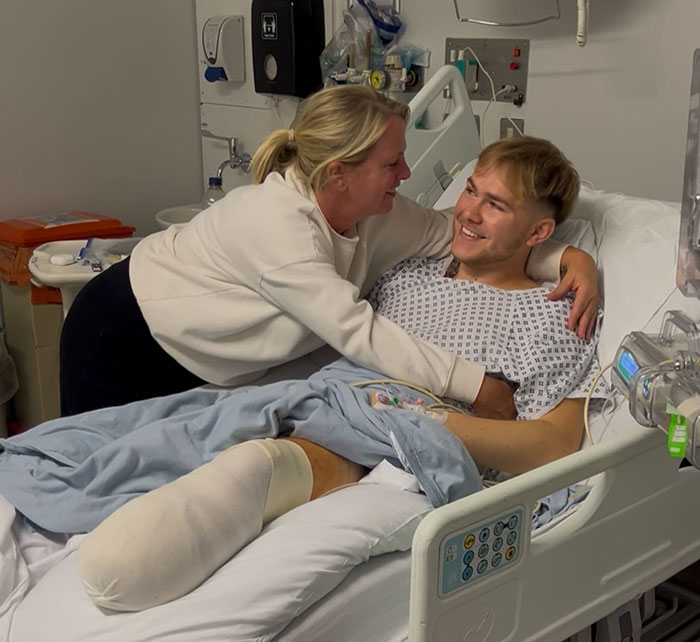 Young man with leg amputation in hospital bed smiling while a woman embraces him, sharing his recovery story. Young man with leg amputation in hospital bed smiling while a woman embraces him, sharing his recovery story.