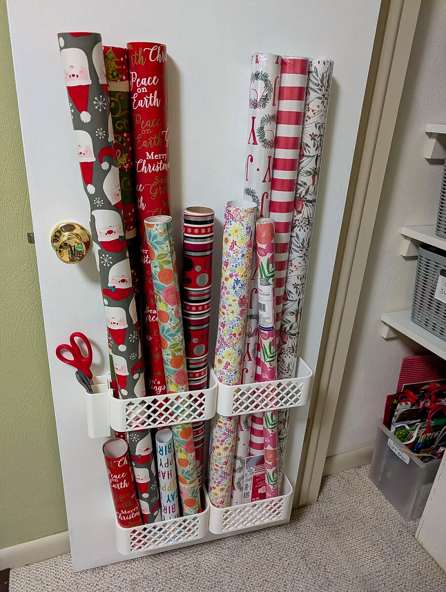 Door mounted organizer holding multiple rolls of wrapping paper and scissors illustrating clever organization hacks for home.