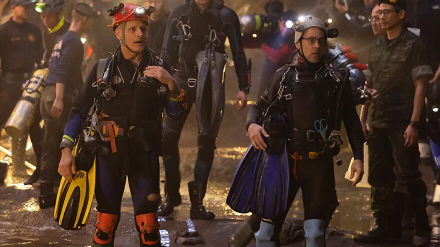 Divers wearing wetsuits and carrying fins, preparing for a rescue in a true story based movie scene.