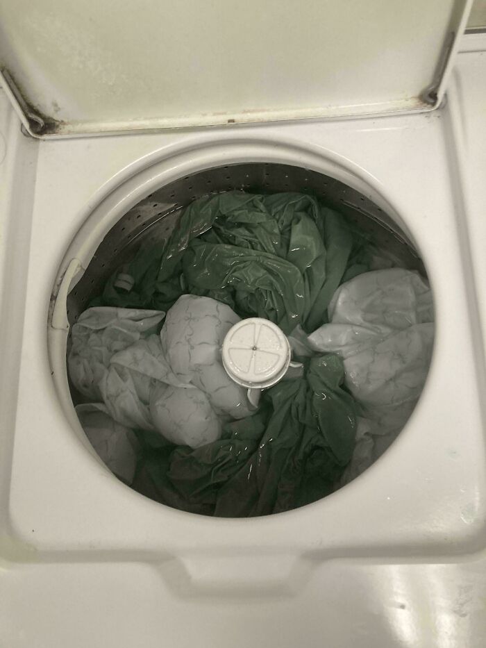 Top-loading washing machine filled with water and soaked clothes, illustrating people allergic to acting like sensible adults.