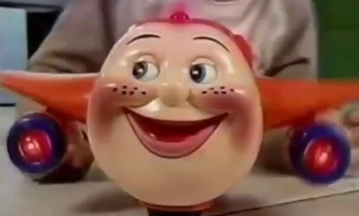 Vintage creepy toy clown with exaggerated smile and wide eyes, featured in unsettling commercials that might give nightmares.