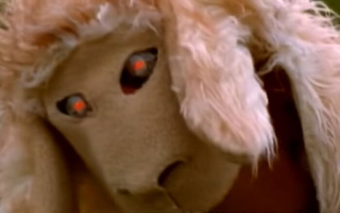 Close-up of a creepy puppet with glowing red eyes from a nightmare-inducing commercial scene.