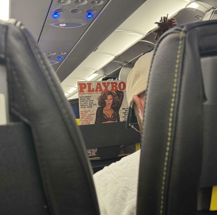 Passenger on a plane reading a Playboy magazine, illustrating people who are allergic to acting like sensible adults.
