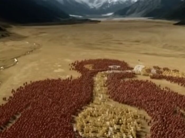 Massive groups of people forming eerie shapes in a barren landscape, evoking creepy commercial scenes.
