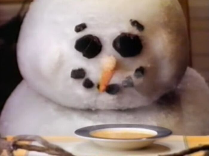 A close-up of a creepy snowman with coal eyes and mouth, featured in unsettling commercials that might give nightmares.