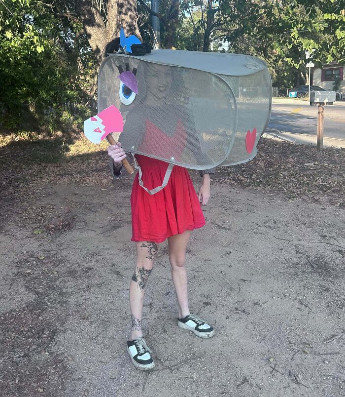 Creative Halloween costume featuring a person in a red dress with a mesh laundry basket and axe prop outdoors.