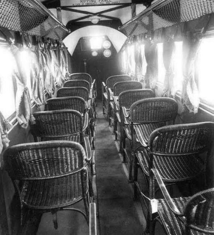 Interior of a vintage airplane showing wicker seats arranged in rows with curtains on the windows, a fascinating photo.