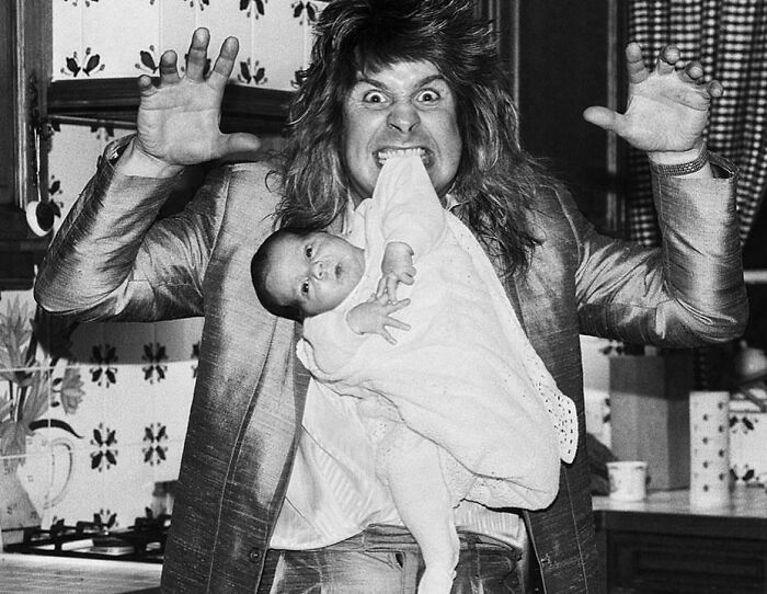 Man playfully posing with a baby in his mouth, creating a fascinating and unusual moment captured in a vintage black and white photo.