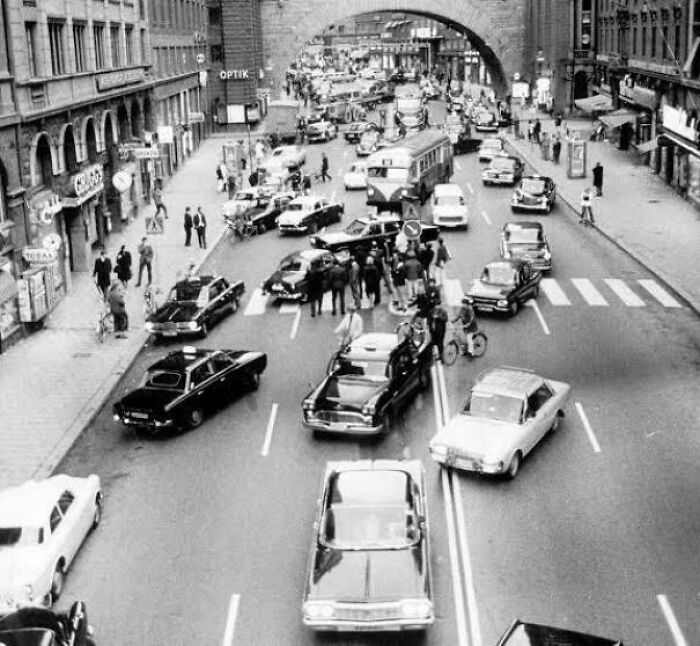 Vintage black and white photo showing a busy city street with classic cars and pedestrians, capturing fascinating moments.