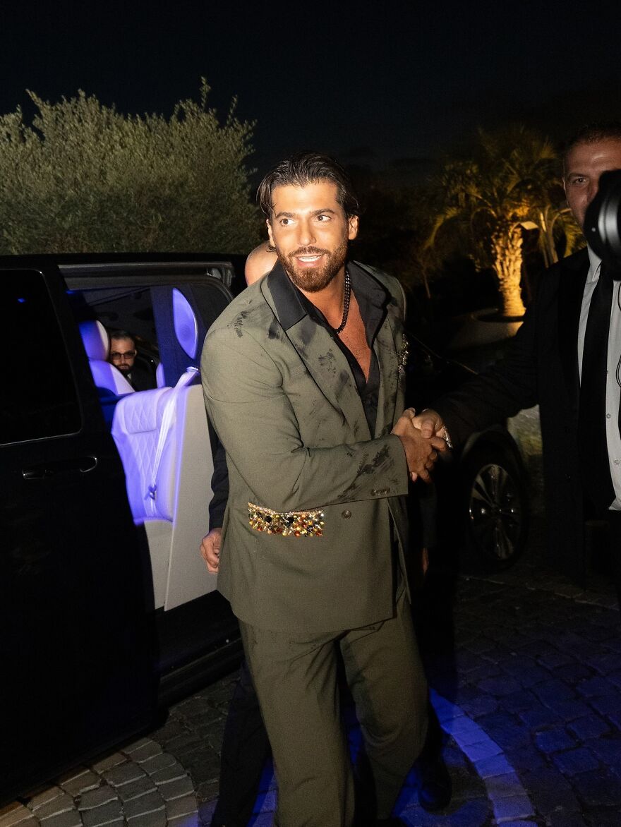 Can Yaman in stylish suit shaking hands outside a car at night in the most handsome man in the world 2025 event.