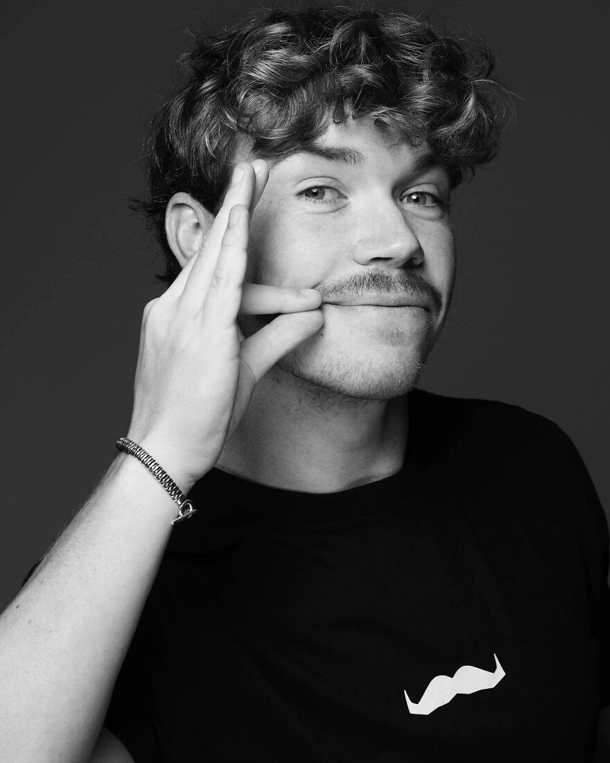 Will Poulter with curly hair and mustache posing confidently, representing most handsome man in the world 2025.