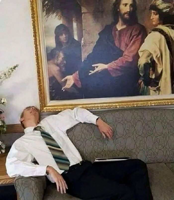 Man in white shirt and striped tie leaning back asleep on couch below an out of context painting with pleasures of the occult theme.